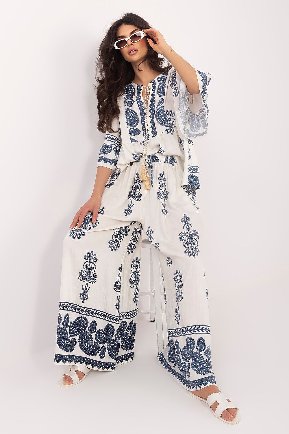 Woman wearing a white outfit with blue patterns on a white background