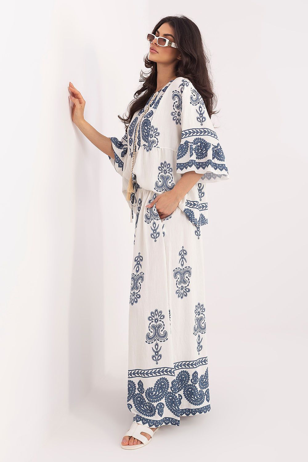 Woman wearing a white dress with blue patterns against a white background