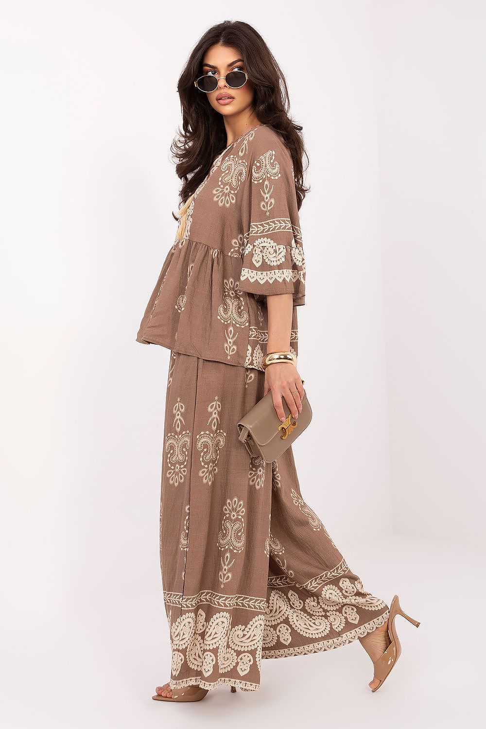 Woman wearing a brown outfit with white embroidery on a white background