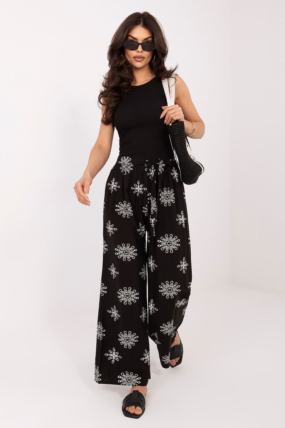 Woman wearing a black jumpsuit with white patterns on a white background