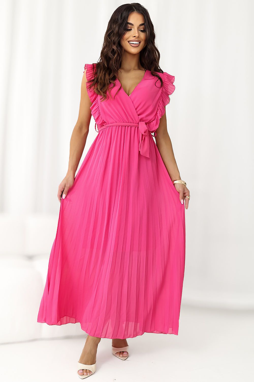Woman wearing a bright pink dress with ruffled sleeves on a white background