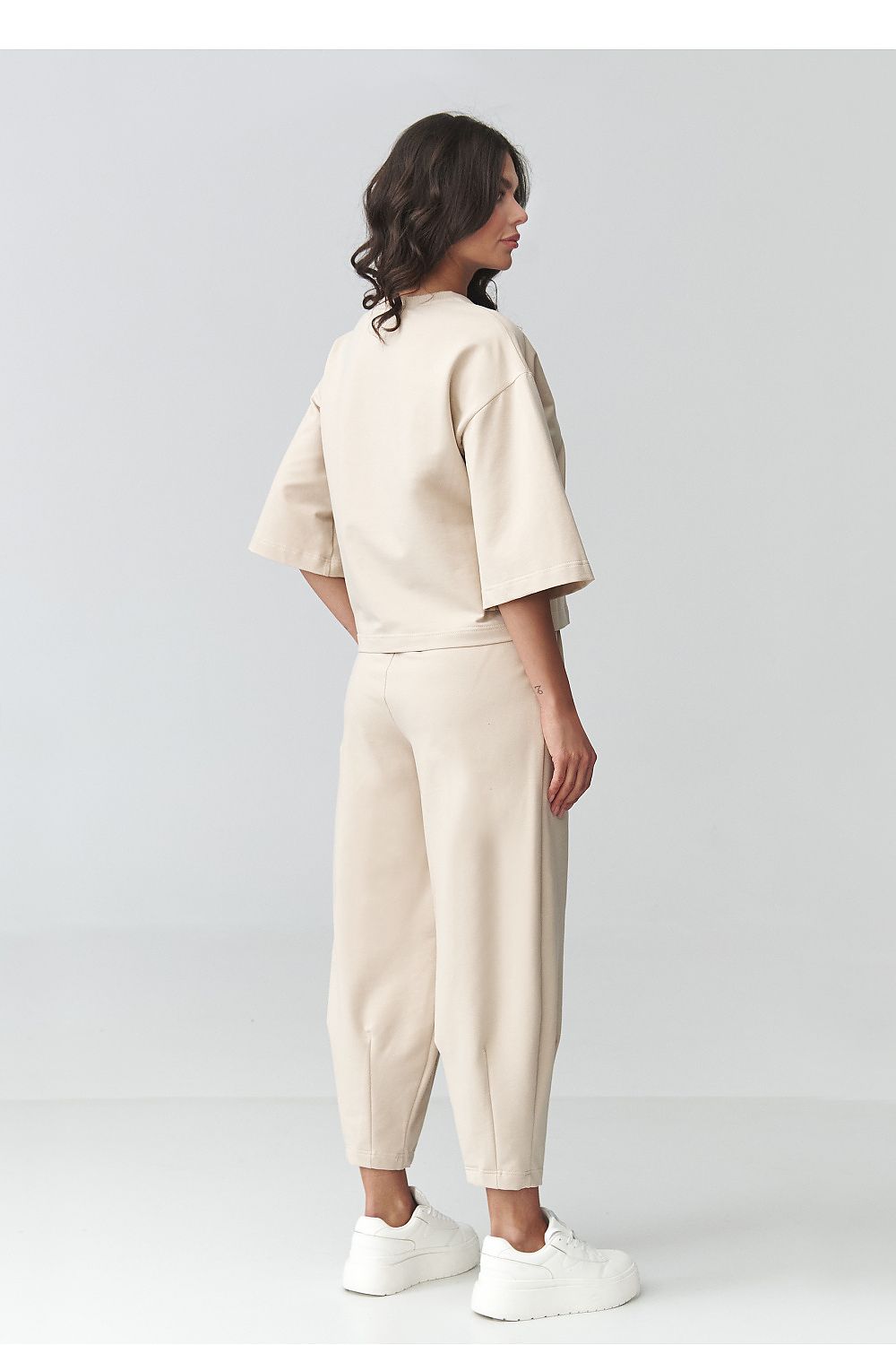 Person wearing a beige outfit on a plain background