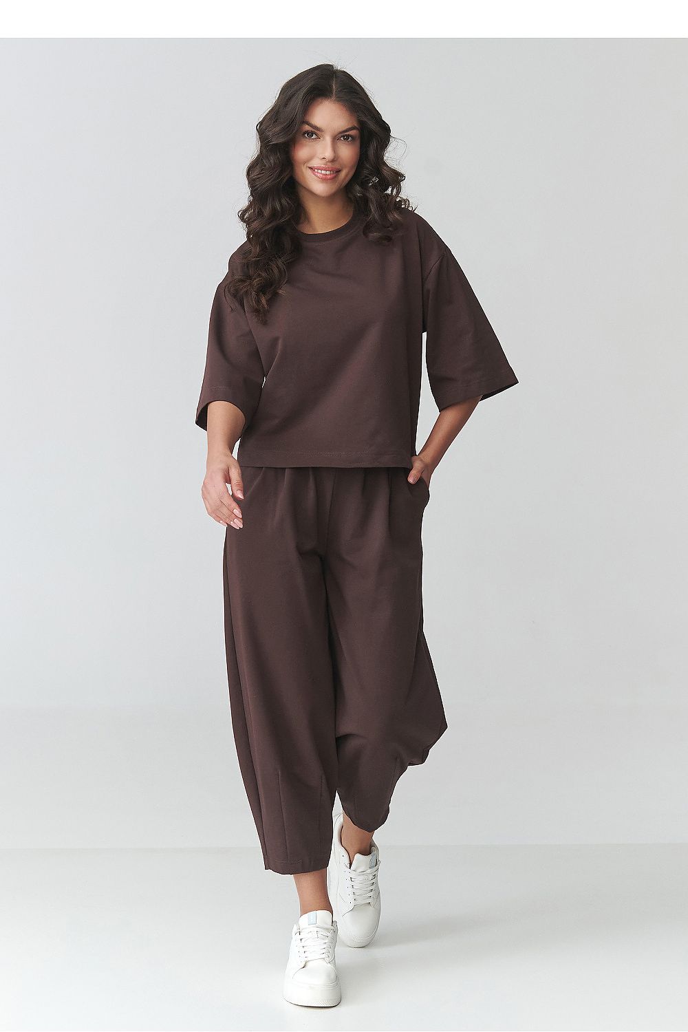 Woman wearing a brown outfit with wide-leg pants on a white background