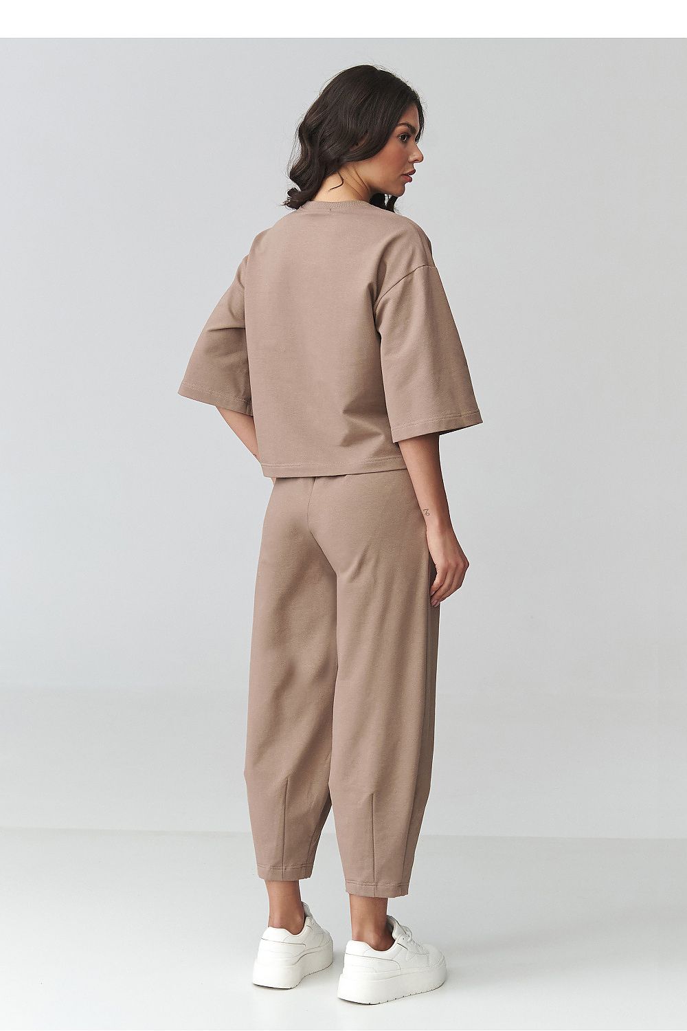 Woman wearing a beige outfit on a plain background