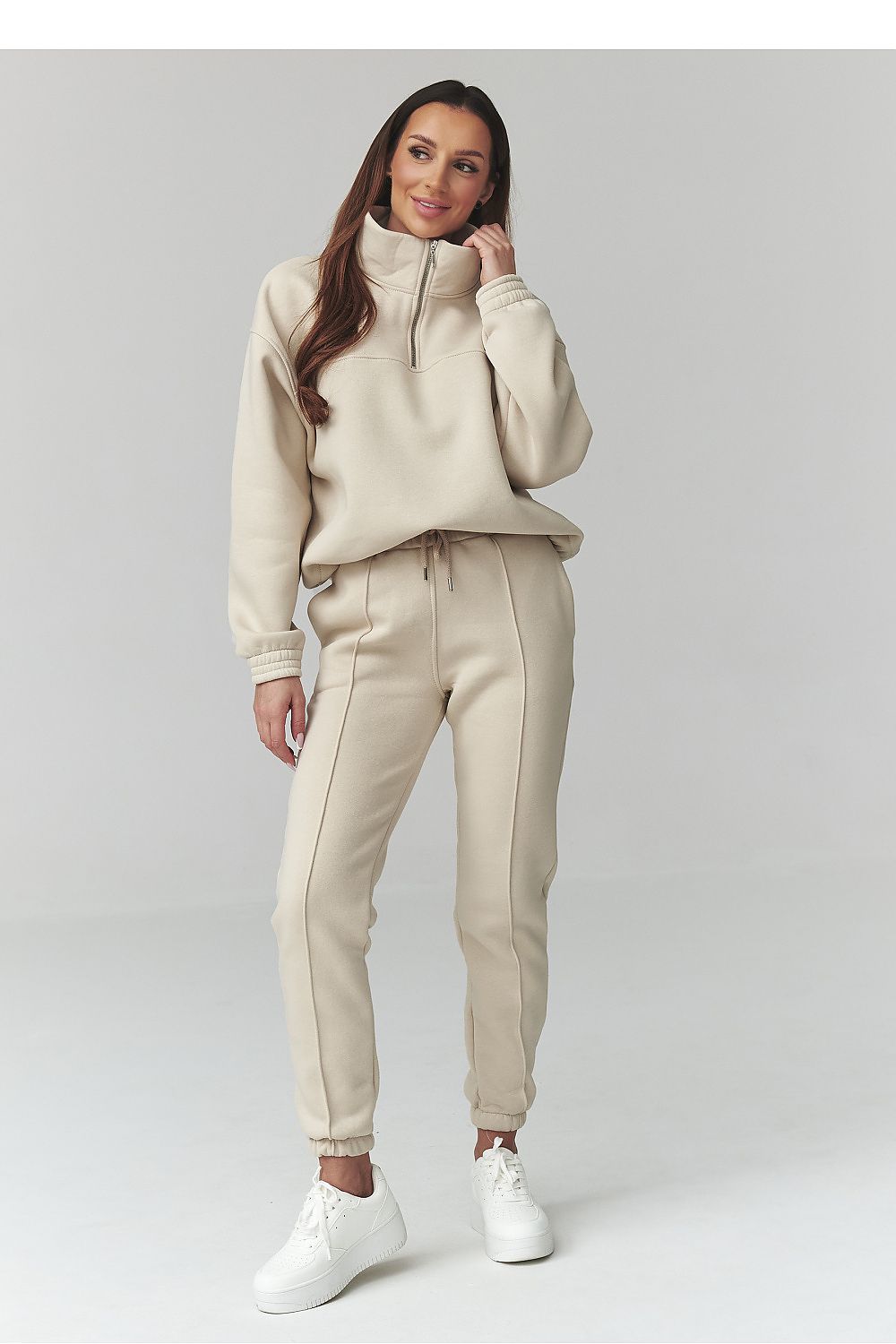 Woman wearing a beige tracksuit on a white background