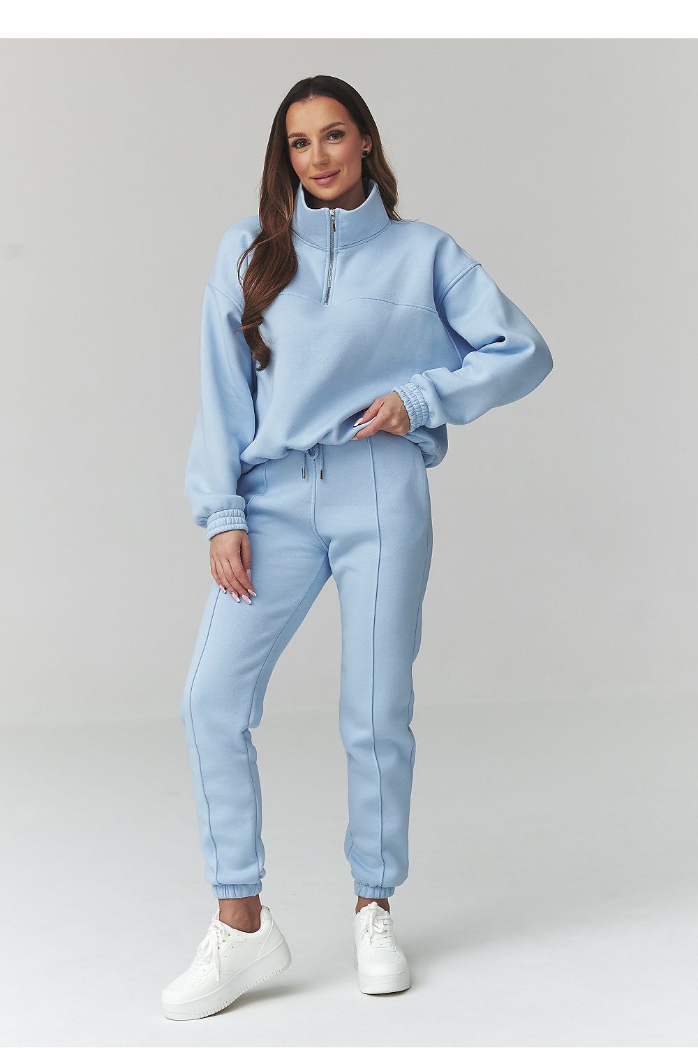 Woman wearing a light blue tracksuit on a white background