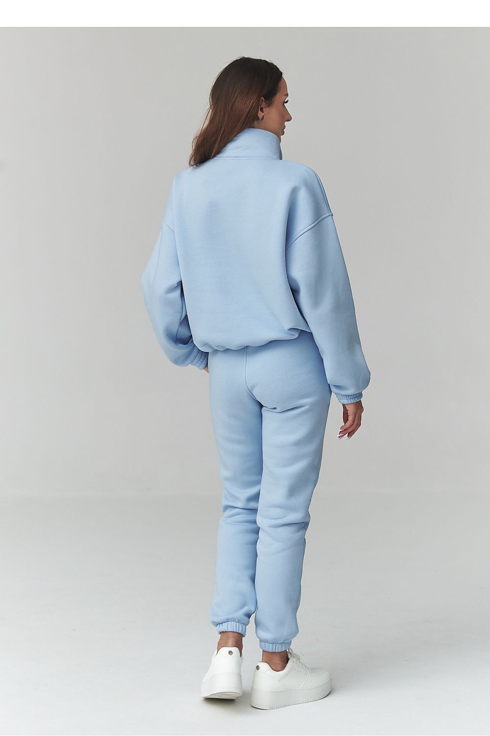 Person wearing a light blue tracksuit on a plain background