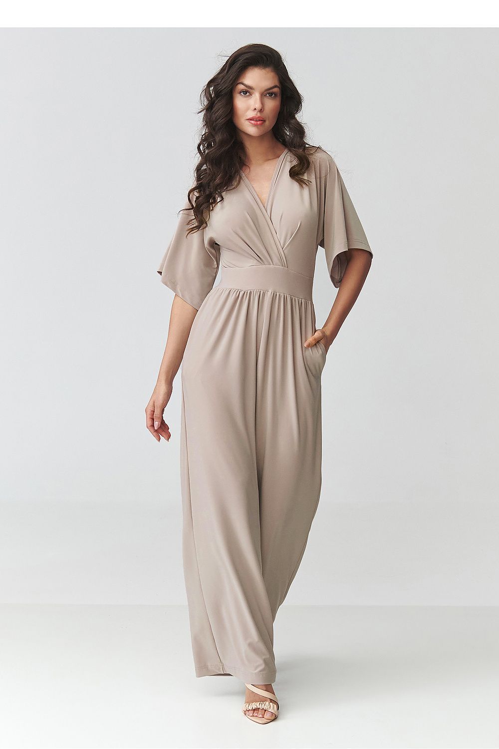 Woman wearing a beige jumpsuit on a white background