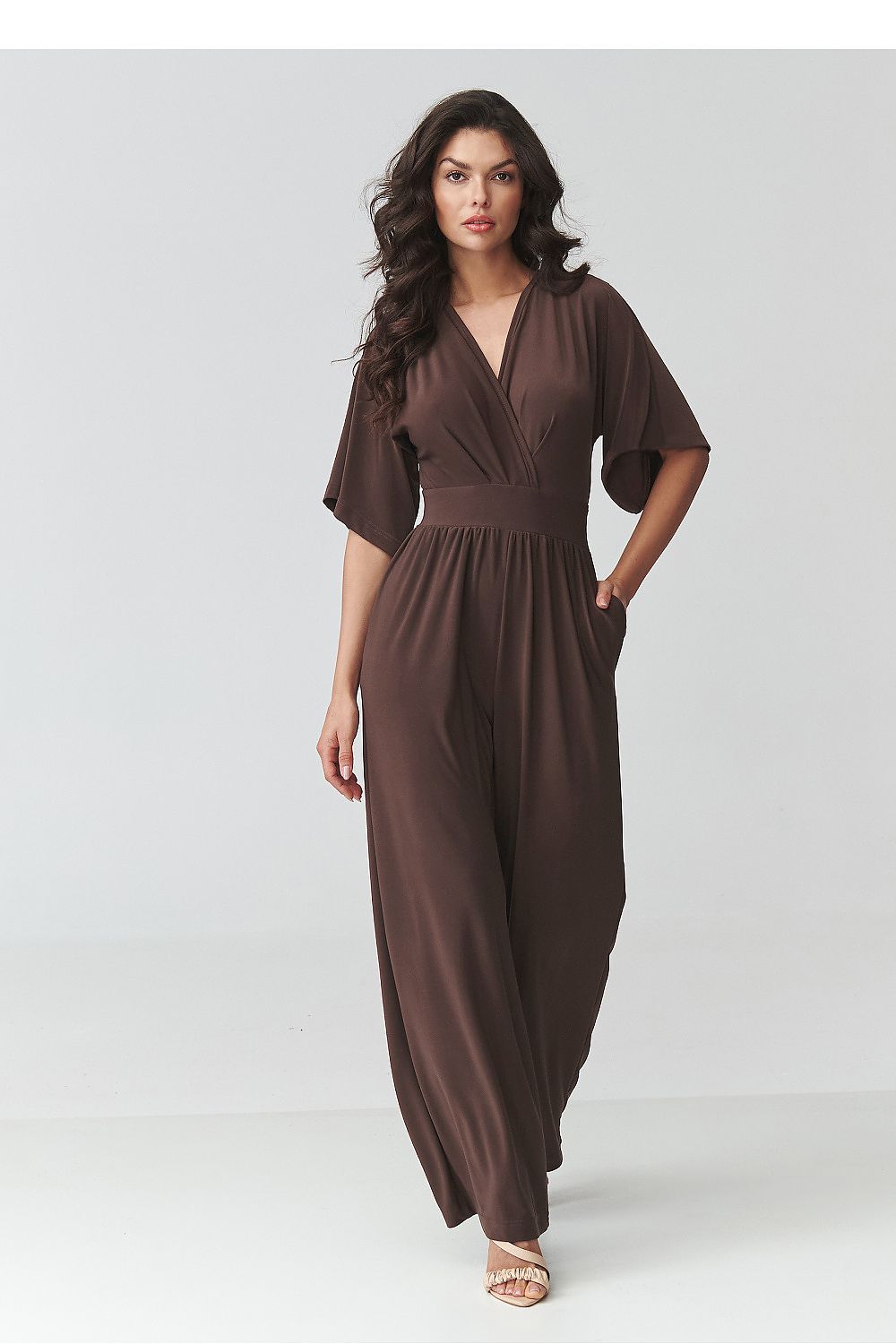 Woman wearing a brown jumpsuit on a white background