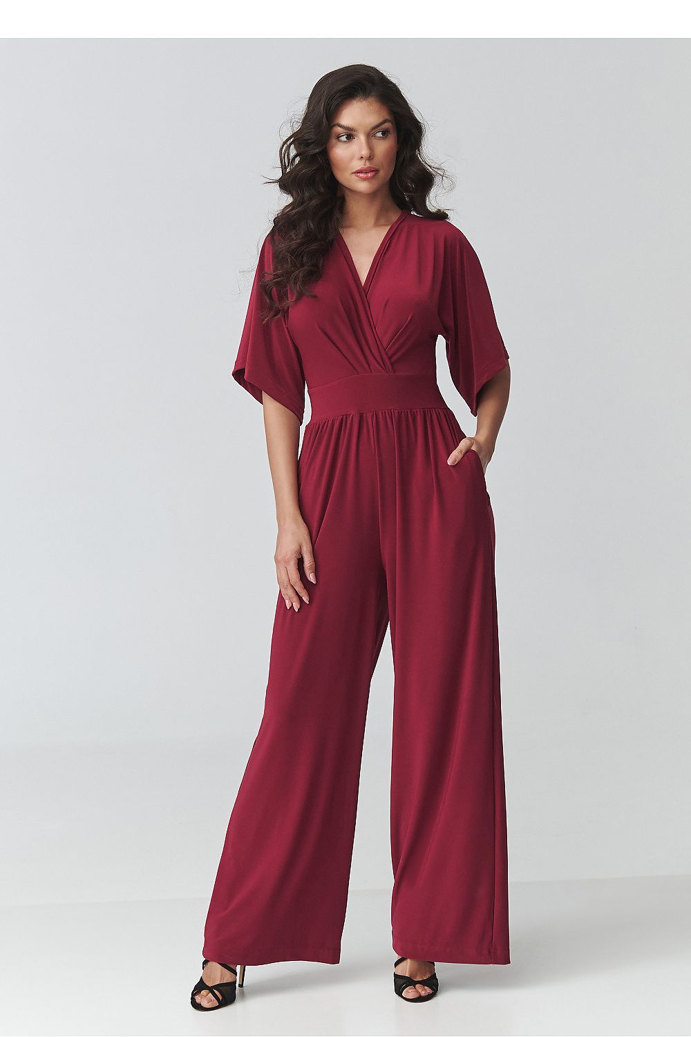 Woman wearing a burgundy jumpsuit on a white background