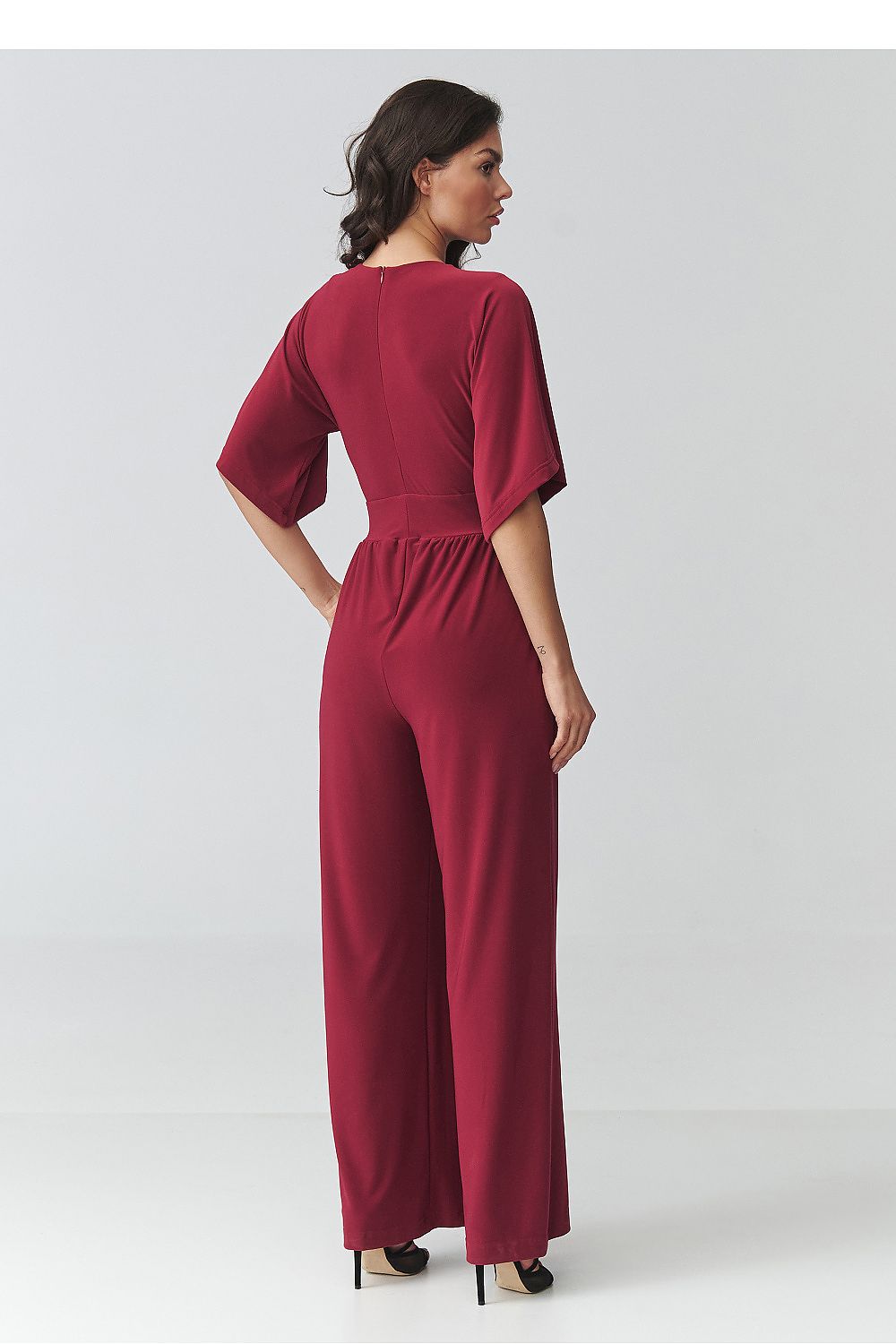 Woman wearing a burgundy jumpsuit on a white background