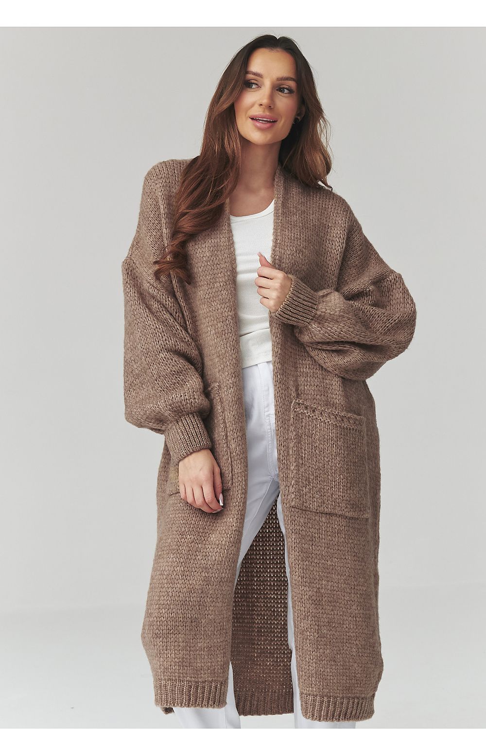 Woman wearing a long brown knitted cardigan on a light gray background