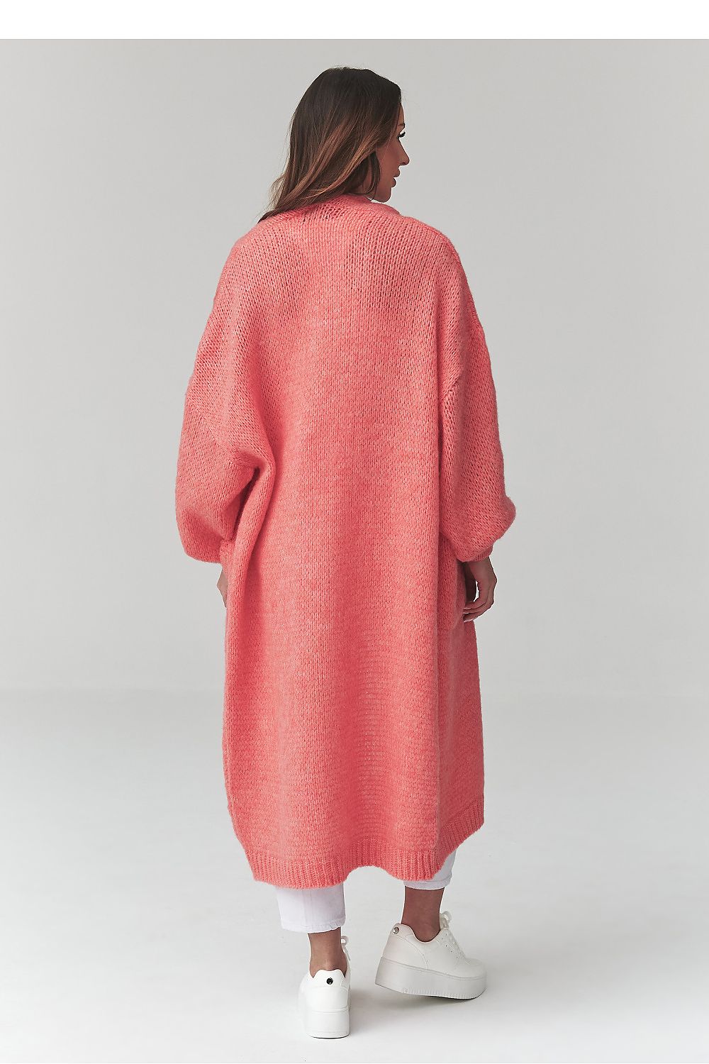 Person wearing a long coral cardigan on a plain background