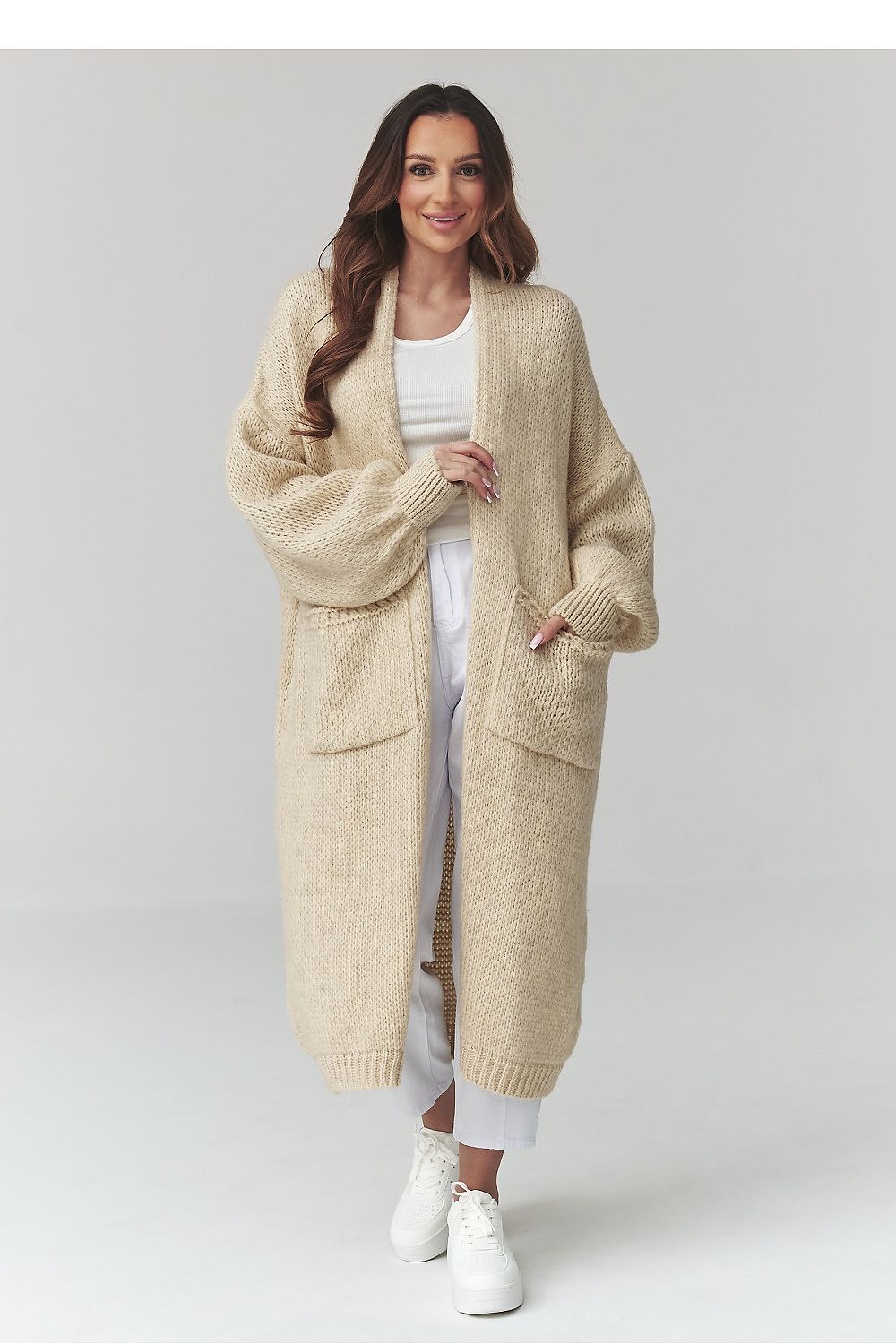 Woman wearing a long beige cardigan on a white background