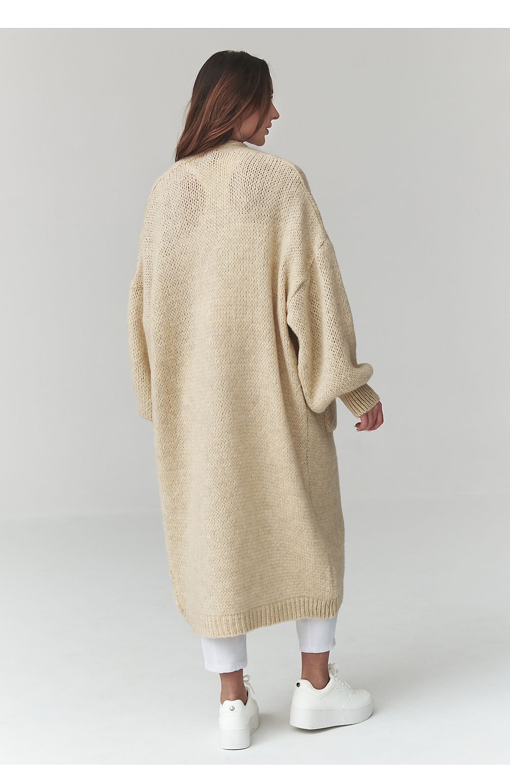 Woman wearing a long beige cardigan on a white background