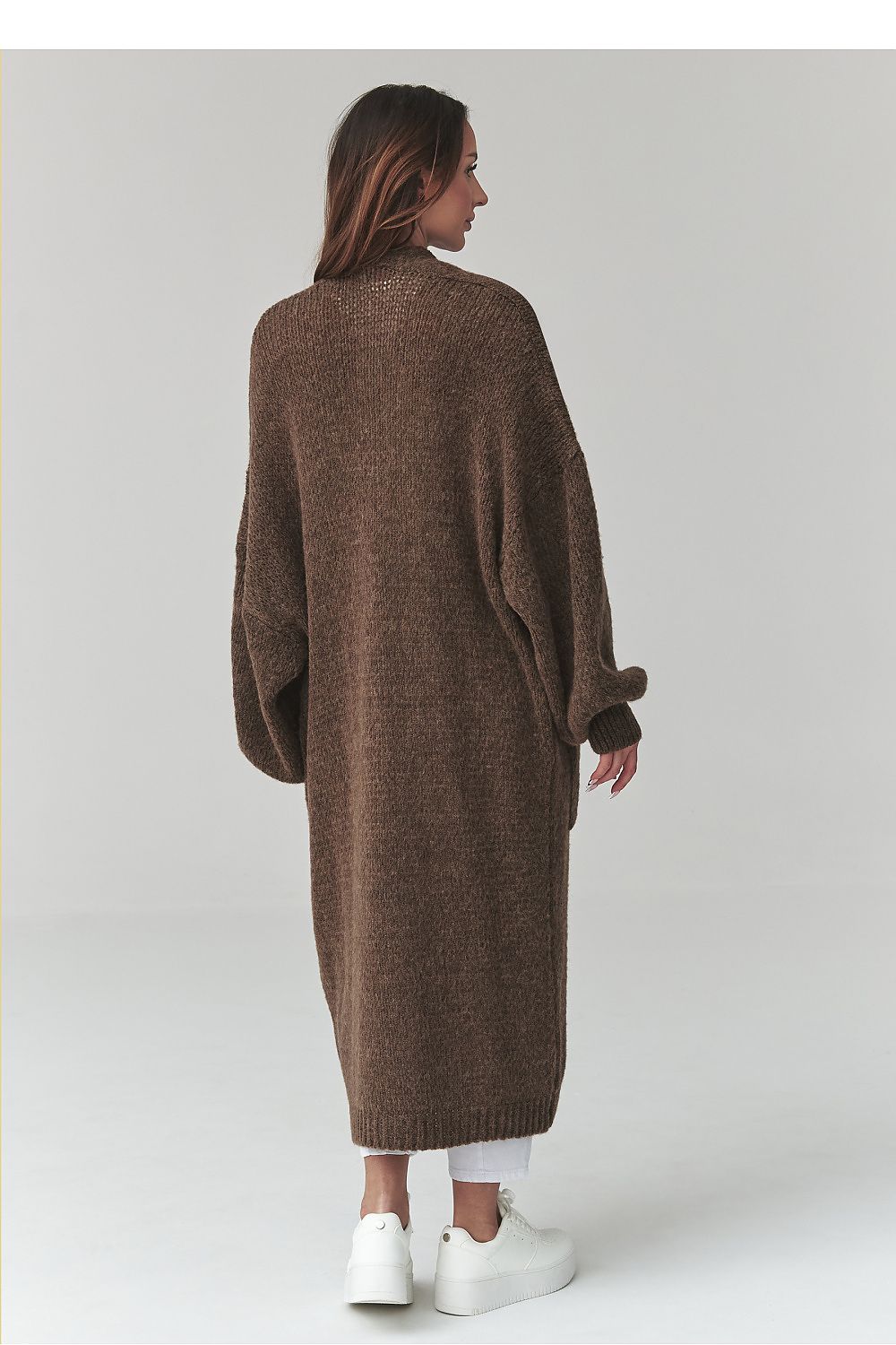 Woman wearing a long brown knitted cardigan on a white background