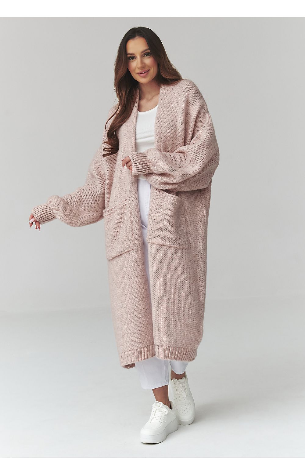 Woman wearing a long pink cardigan on a white background