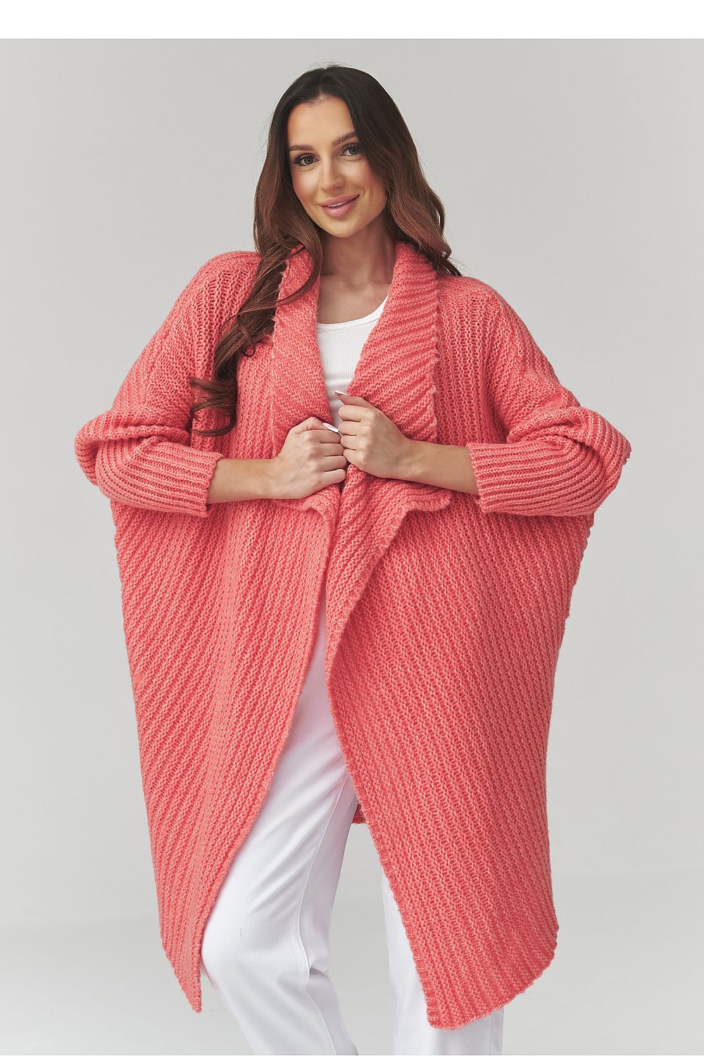 Woman wearing a pink knitted cardigan on a plain background