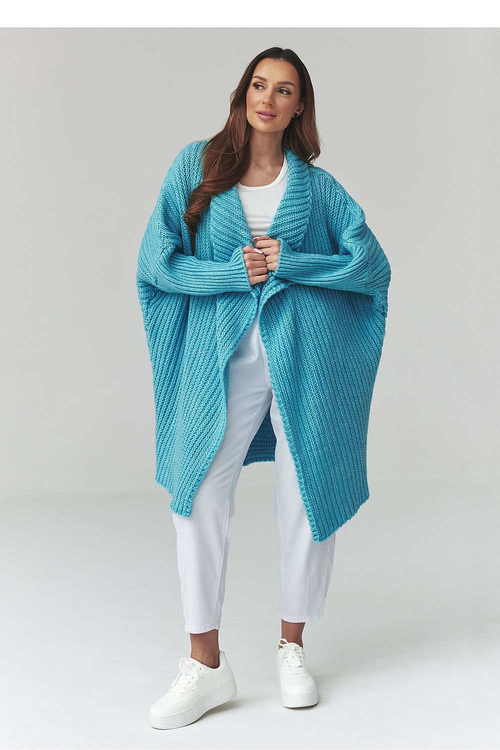 Woman wearing a blue knitted cardigan on a light gray background