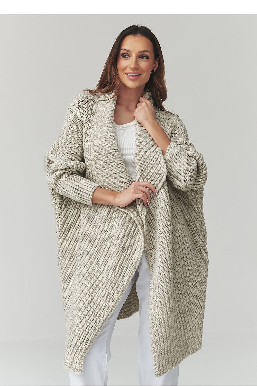 Woman wearing a beige knitted cardigan on a plain background