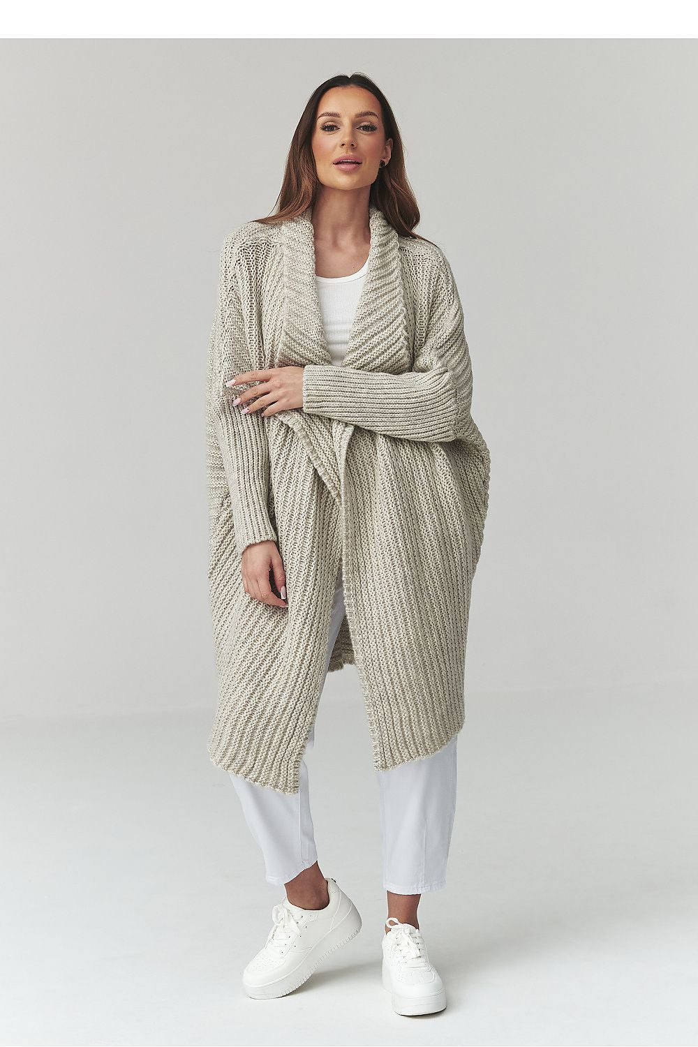 Woman wearing a long beige knitted cardigan on a white background