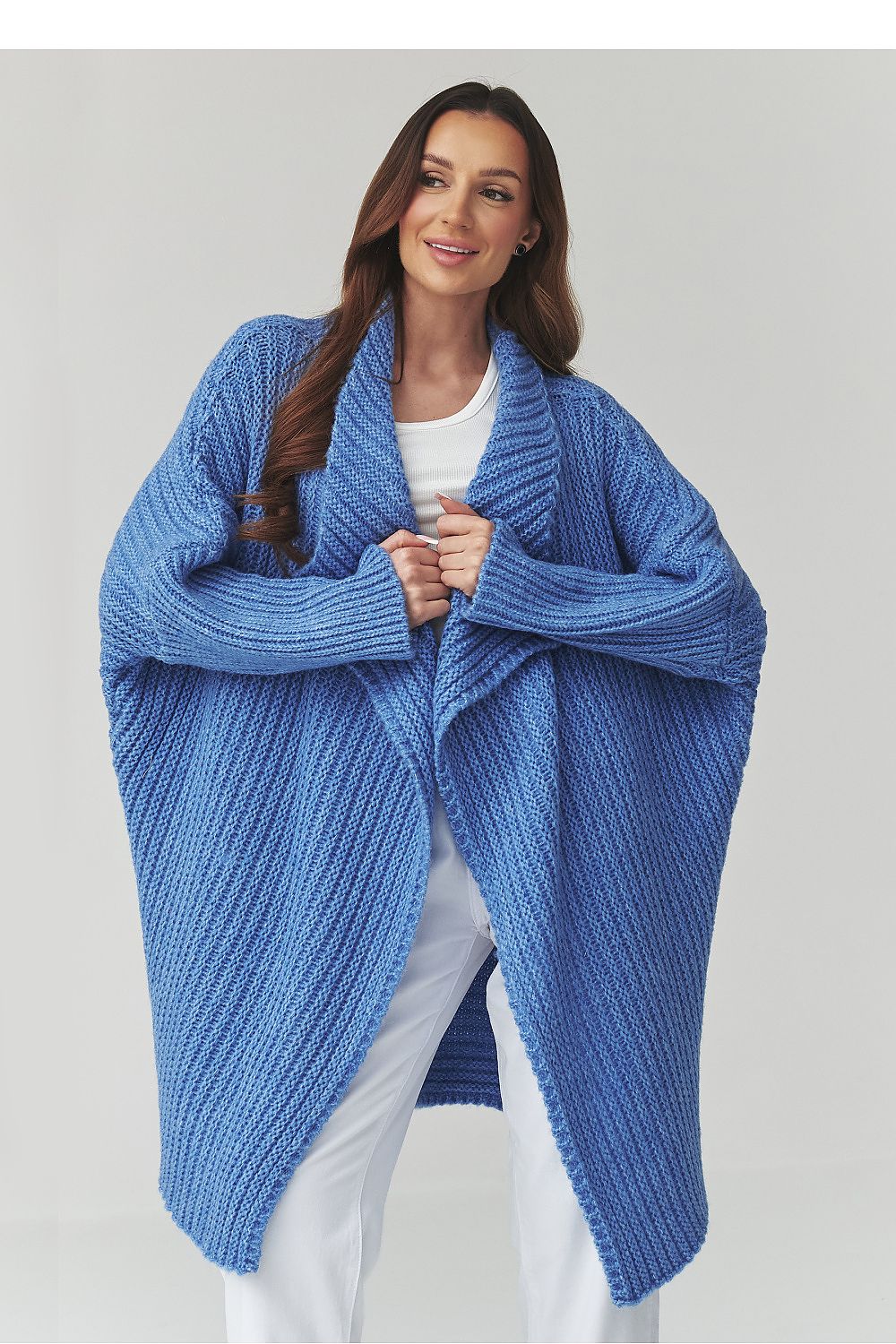 Woman wearing a blue knitted cardigan against a plain background