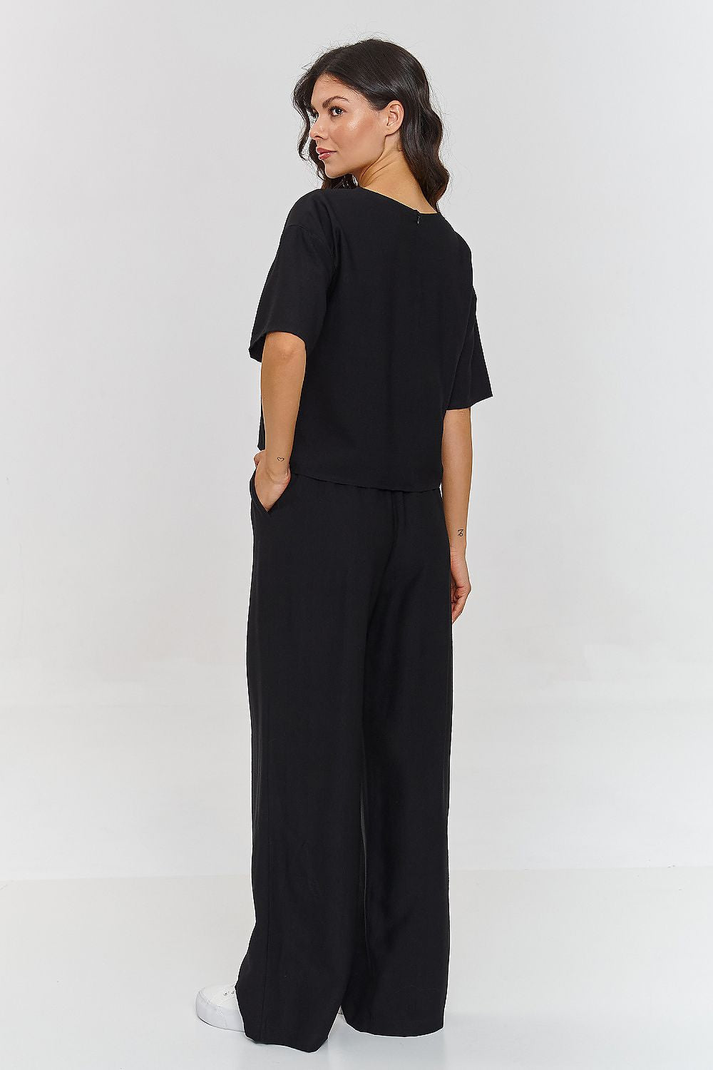Woman wearing a black outfit with wide-leg pants on a white background