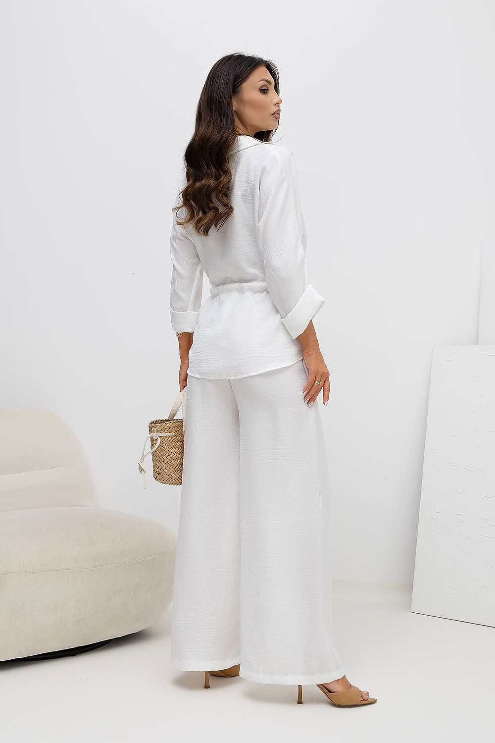 Woman in a white outfit standing in a minimalistic room.