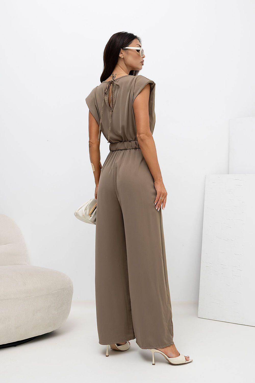 Woman wearing a beige jumpsuit against a white background