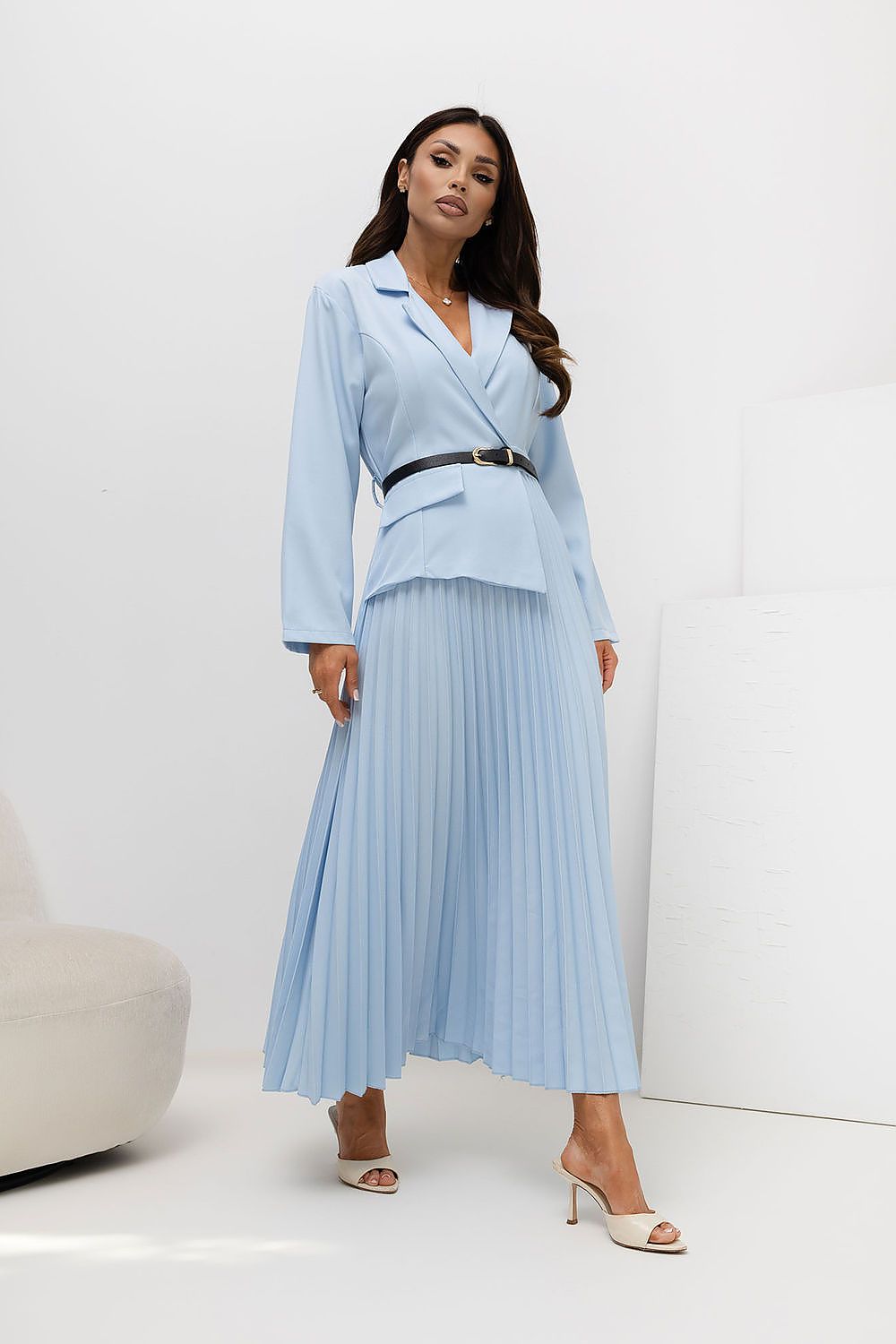 Woman wearing a light blue suit with a pleated skirt on a white background