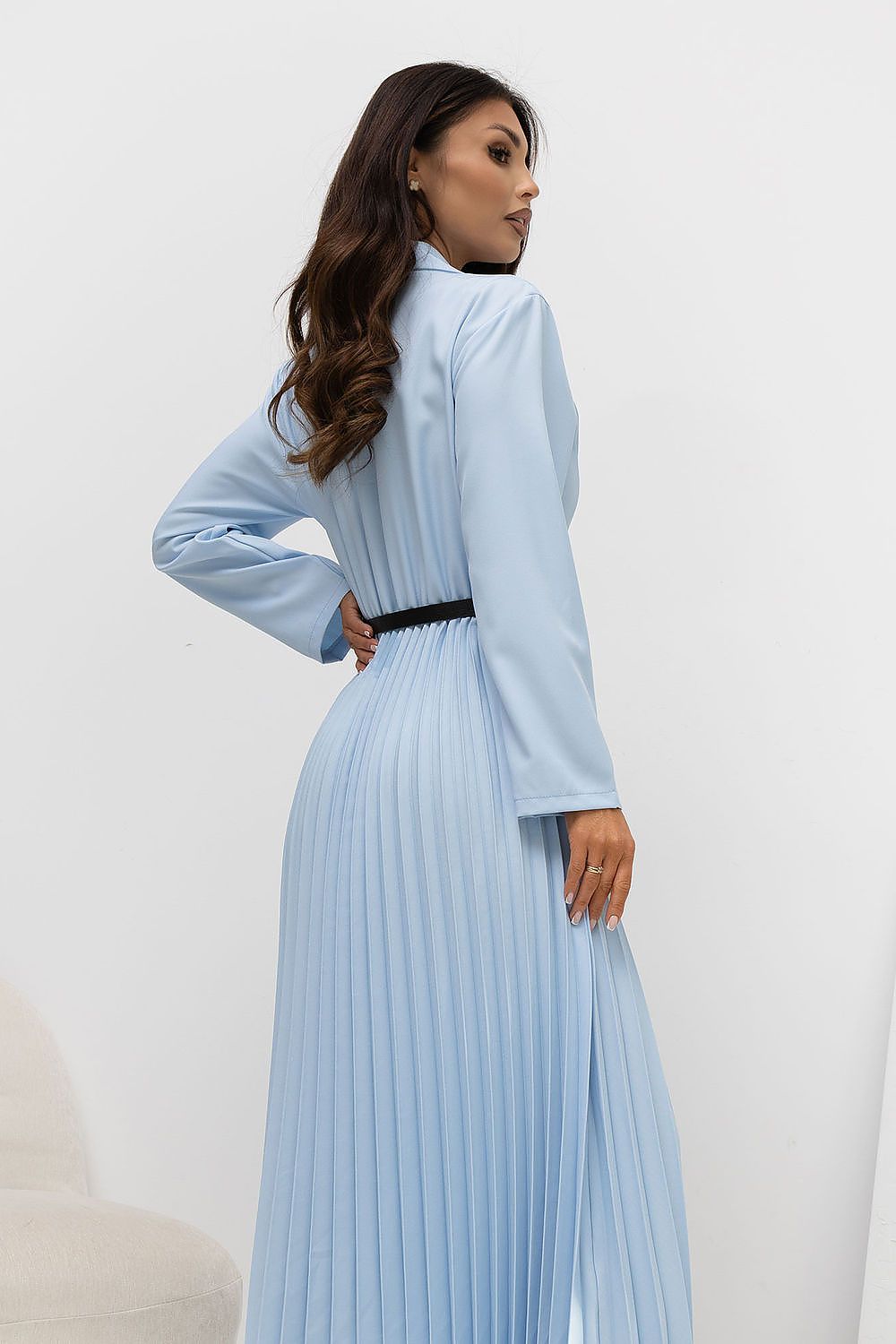 Woman wearing a light blue pleated dress against a white background