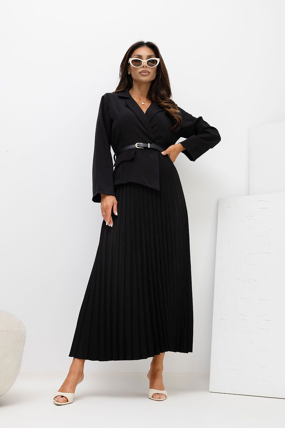 Woman wearing a black suit with sunglasses on a white background