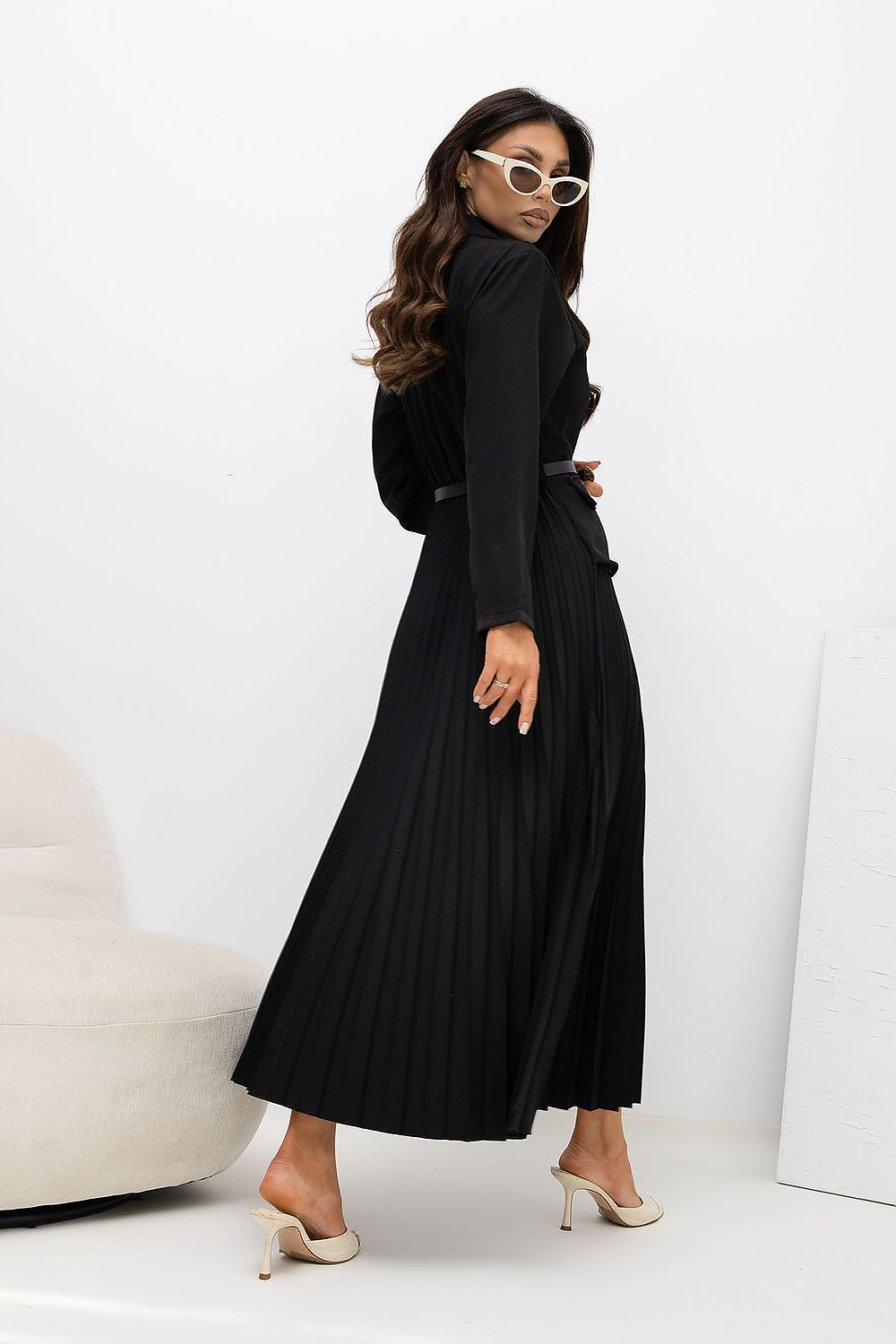 Woman wearing a black dress with a belt against a white background
