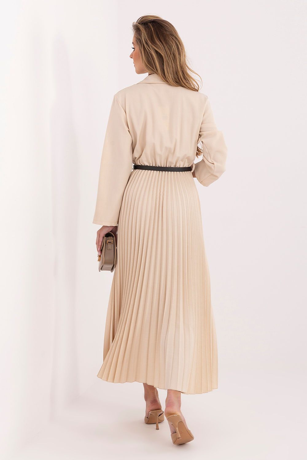 Woman wearing a beige pleated dress with a belt on a white background