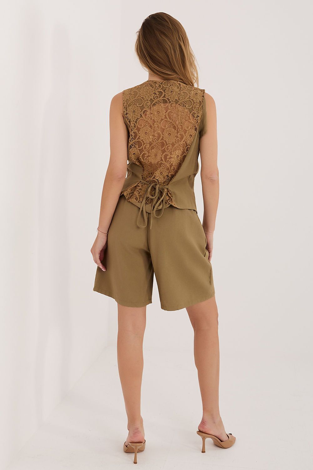 Woman wearing a brown lace top and shorts on a white background