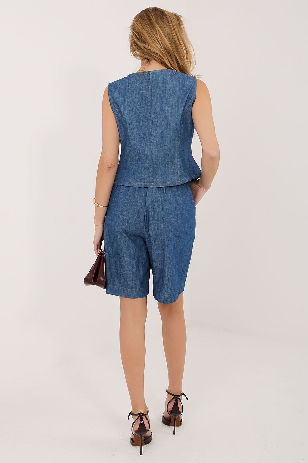 Woman wearing a denim outfit with a peplum top and shorts on a white background