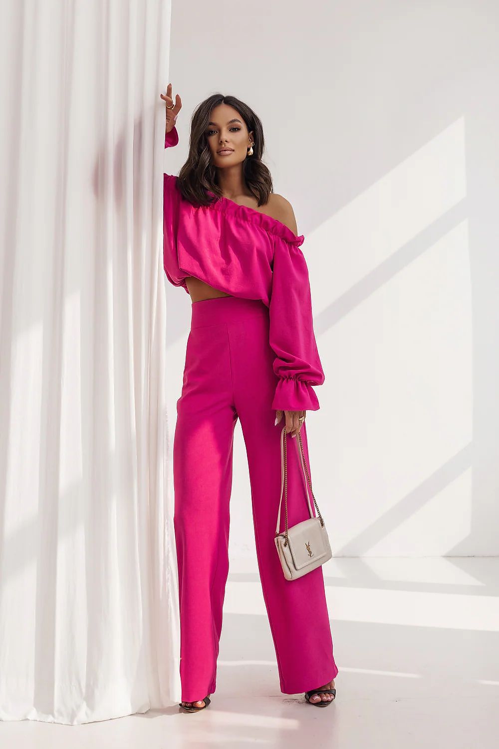 Woman in a bright pink outfit posing against a white background
