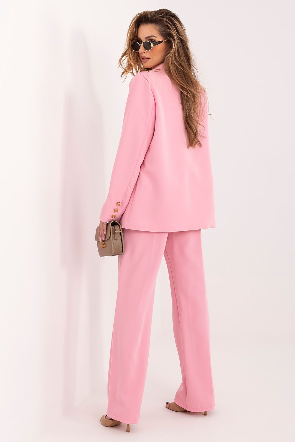 Woman wearing a pink suit with sunglasses on a white background