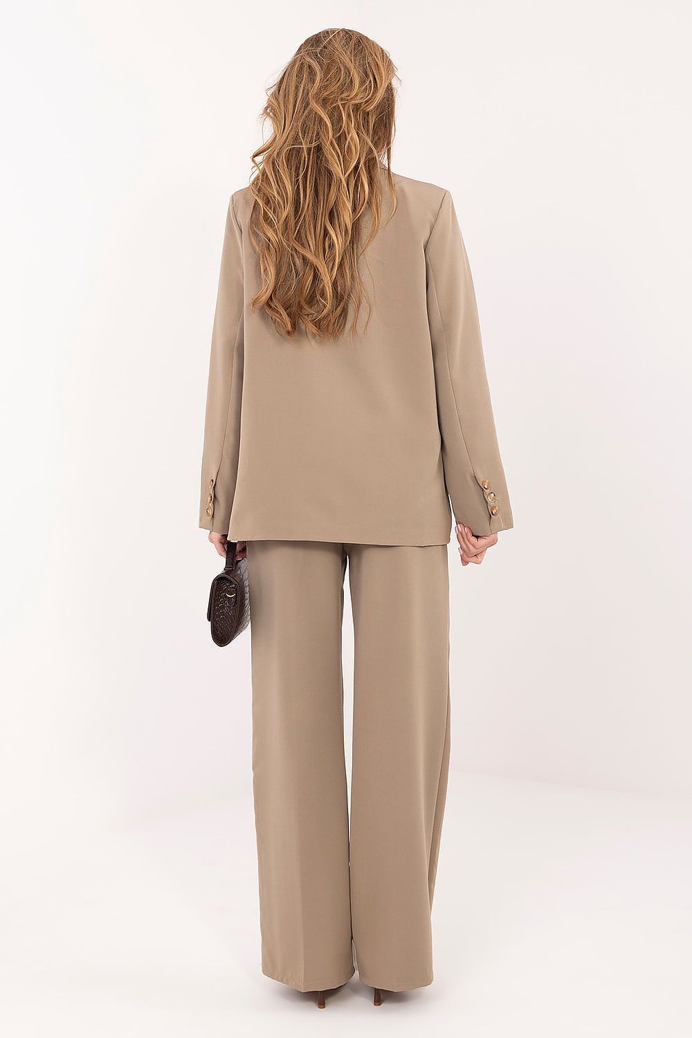 Person wearing a beige suit with wide-leg pants on a white background