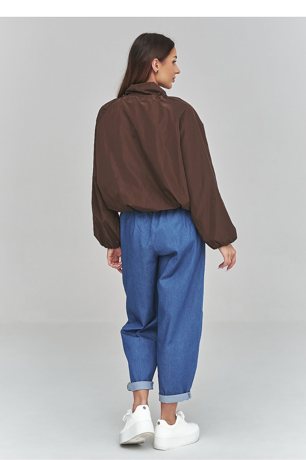 Person wearing a brown shirt and blue jeans on a gray background