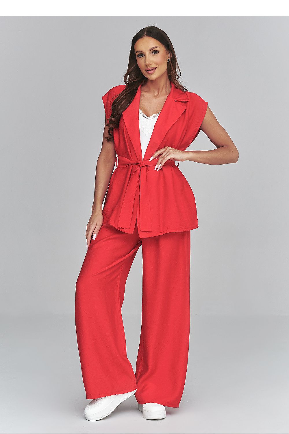 Woman wearing a red suit with a white top on a gray background