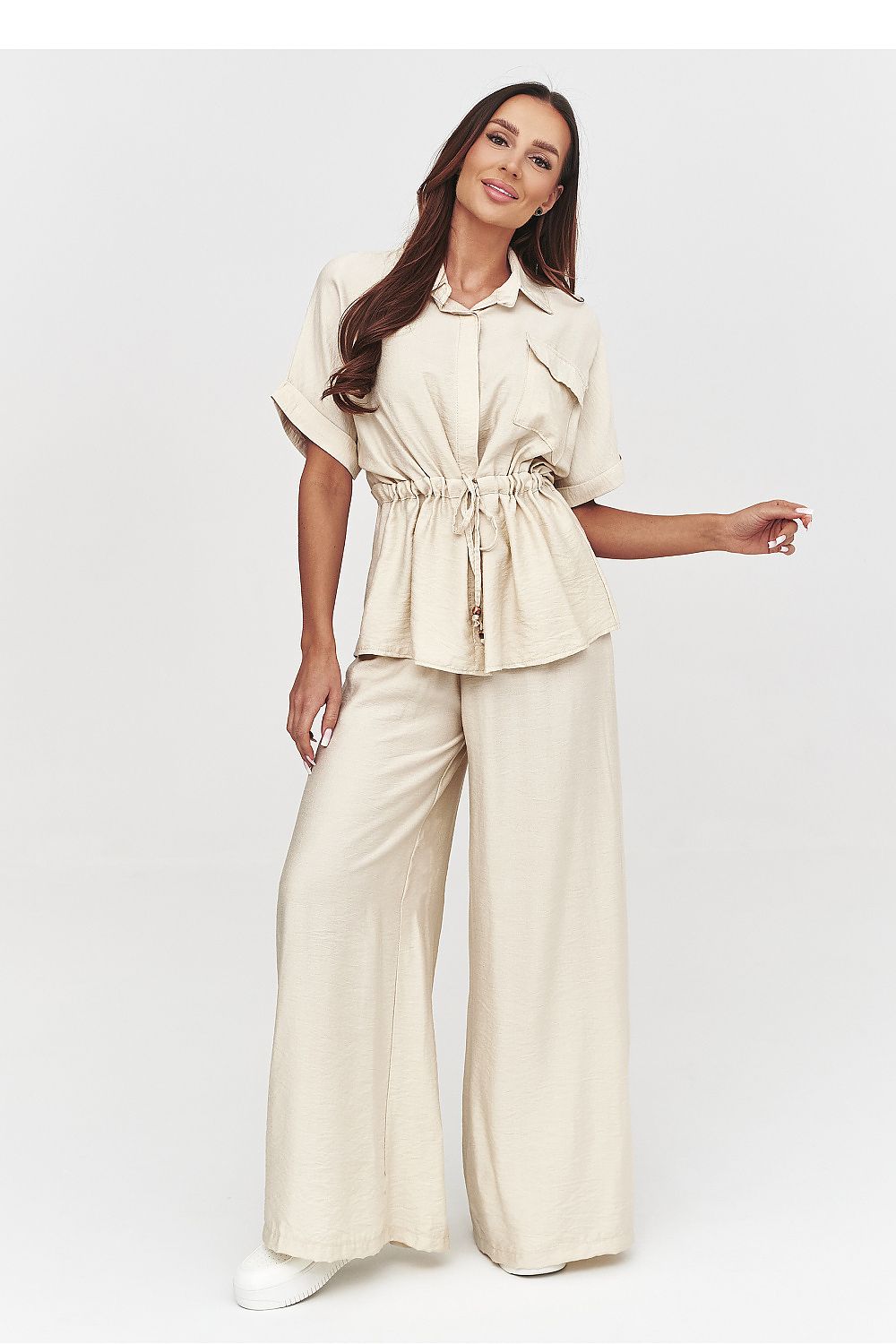 Woman wearing a beige outfit with wide-leg pants on a white background