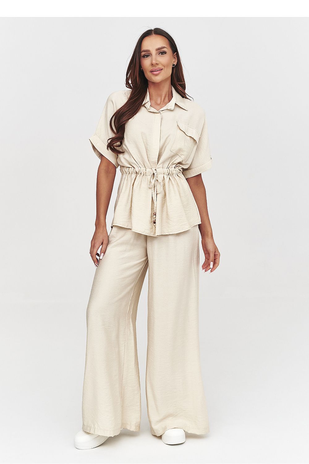 Woman wearing a beige outfit with wide-leg pants on a white background