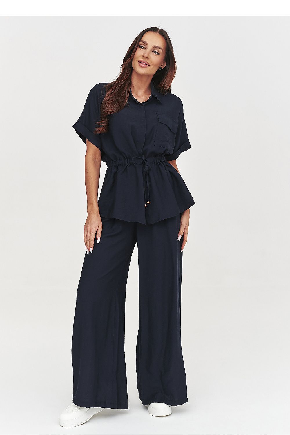 Woman wearing a navy outfit with wide-leg pants on a white background