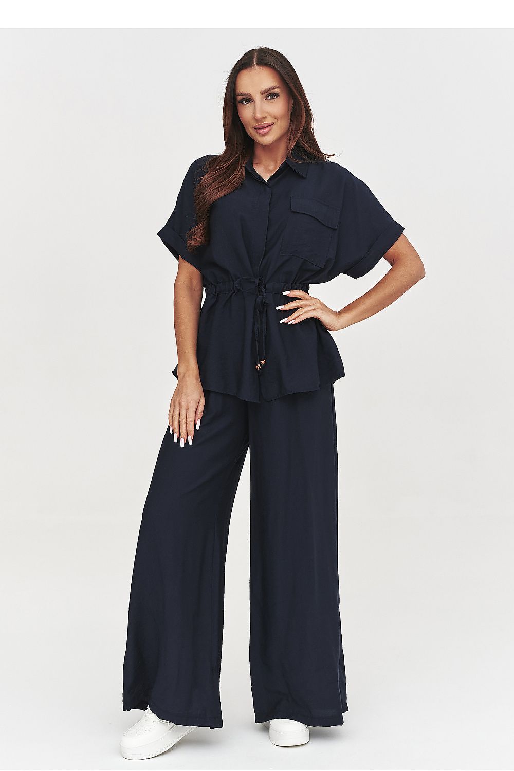 Woman wearing a navy jumpsuit on a white background