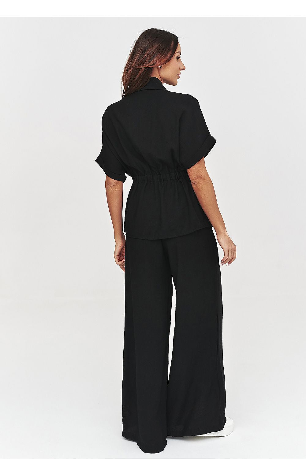 Woman wearing a black outfit with wide-leg pants on a white background
