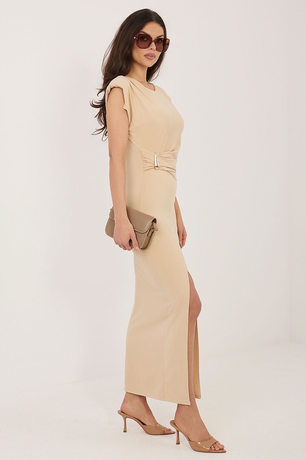Woman wearing a beige dress with a belt on a white background
