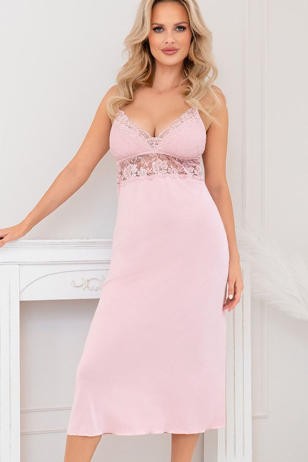 Woman wearing a pink dress with lace details against a white background