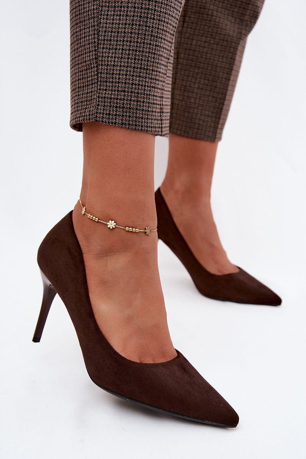 Brown high-heeled shoes worn with plaid pants on a white background