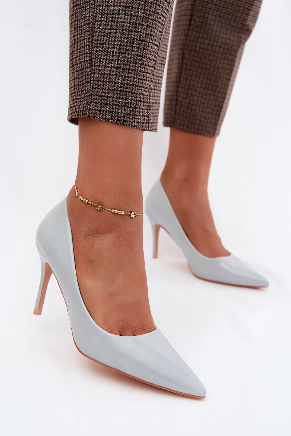 Light gray high-heeled shoes worn with plaid pants on a white background